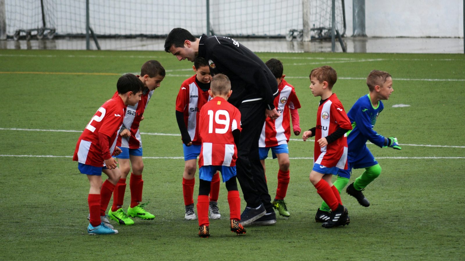 Coach talking to a group of young soccer players at camp