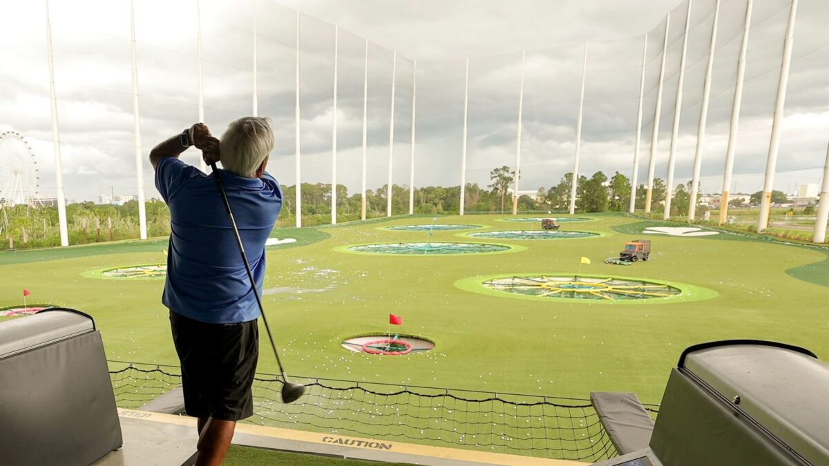 Golfer finishing his swing in an indoor hitting bay