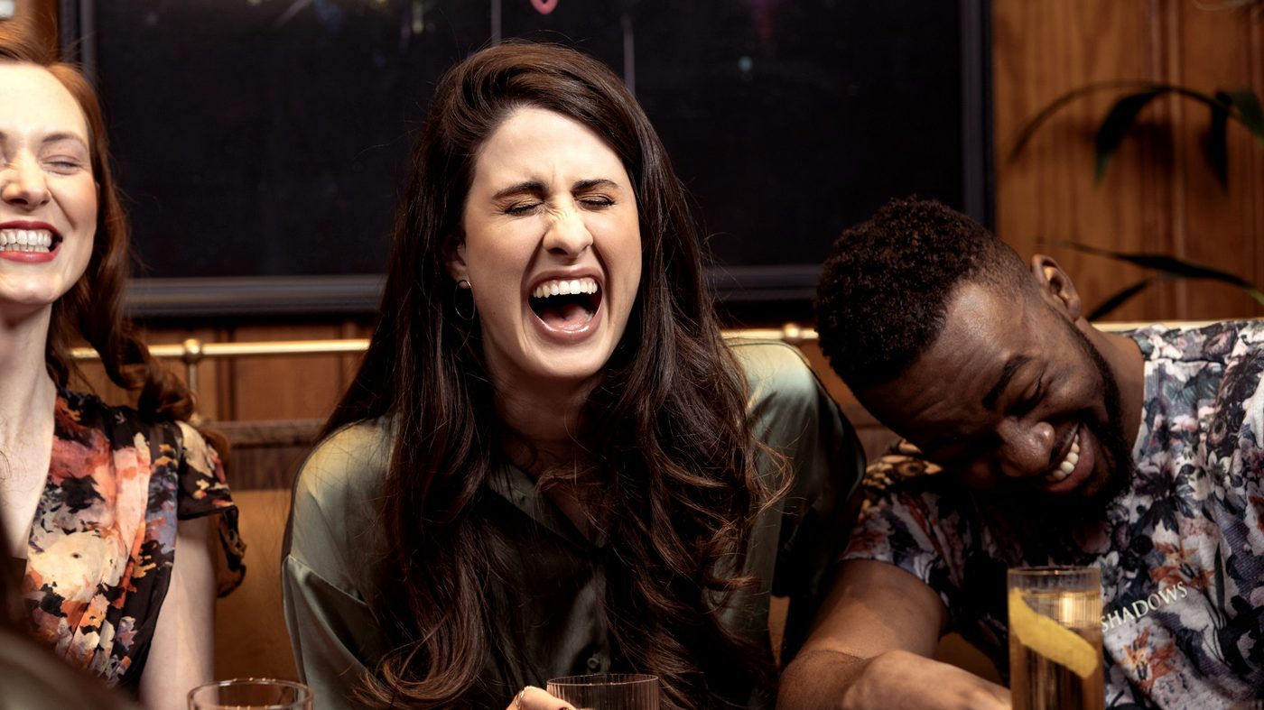 Friends laughing together over drinks on a night out