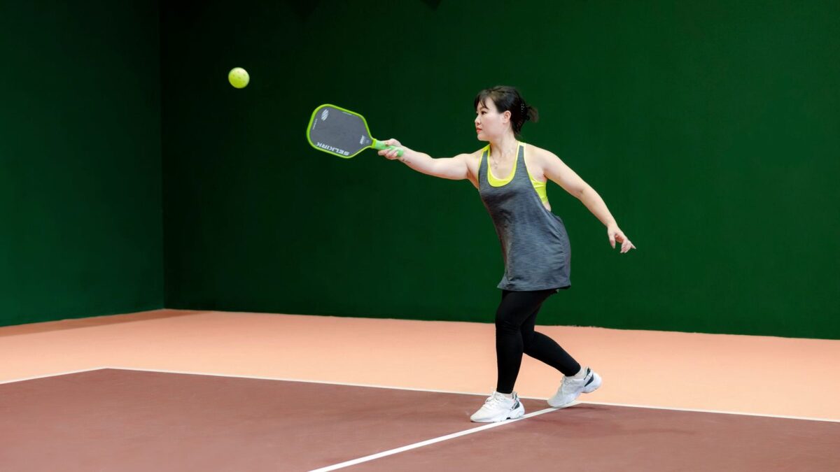 Woman hitting a pickleball on an indoor court