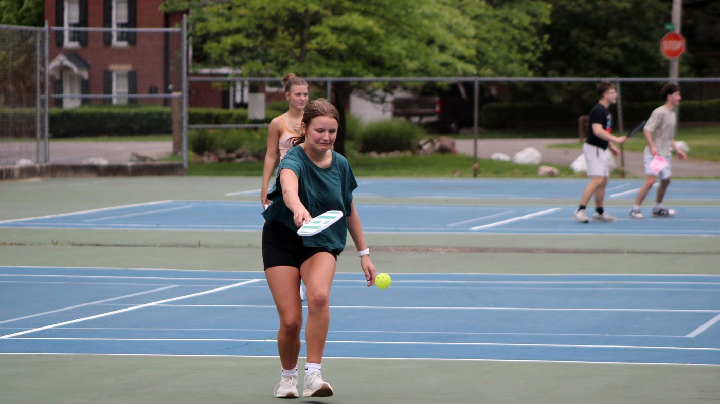 Friends playing a game of pickleball on outdoor courts