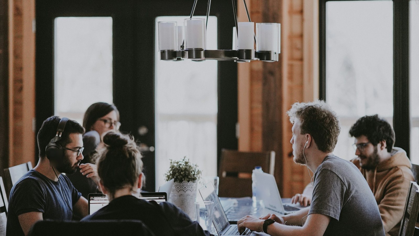Small team working together around a wooden table with laptops